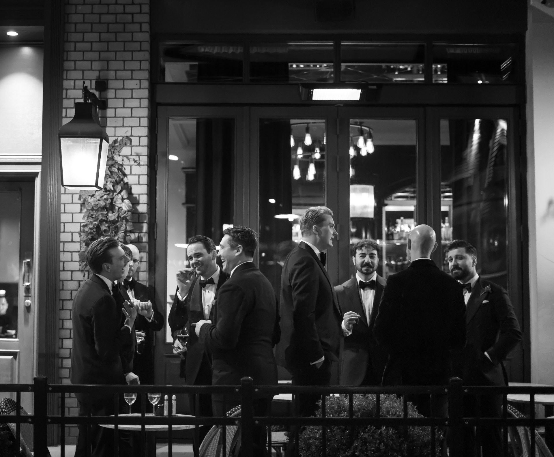 Members in black tie talking outside a lit restaurant on a winter evening